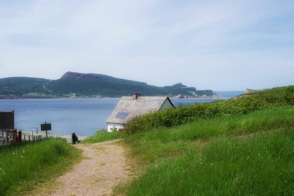 A peaceful house by the sea with lush greenery and a scenic path in a coastal setting.